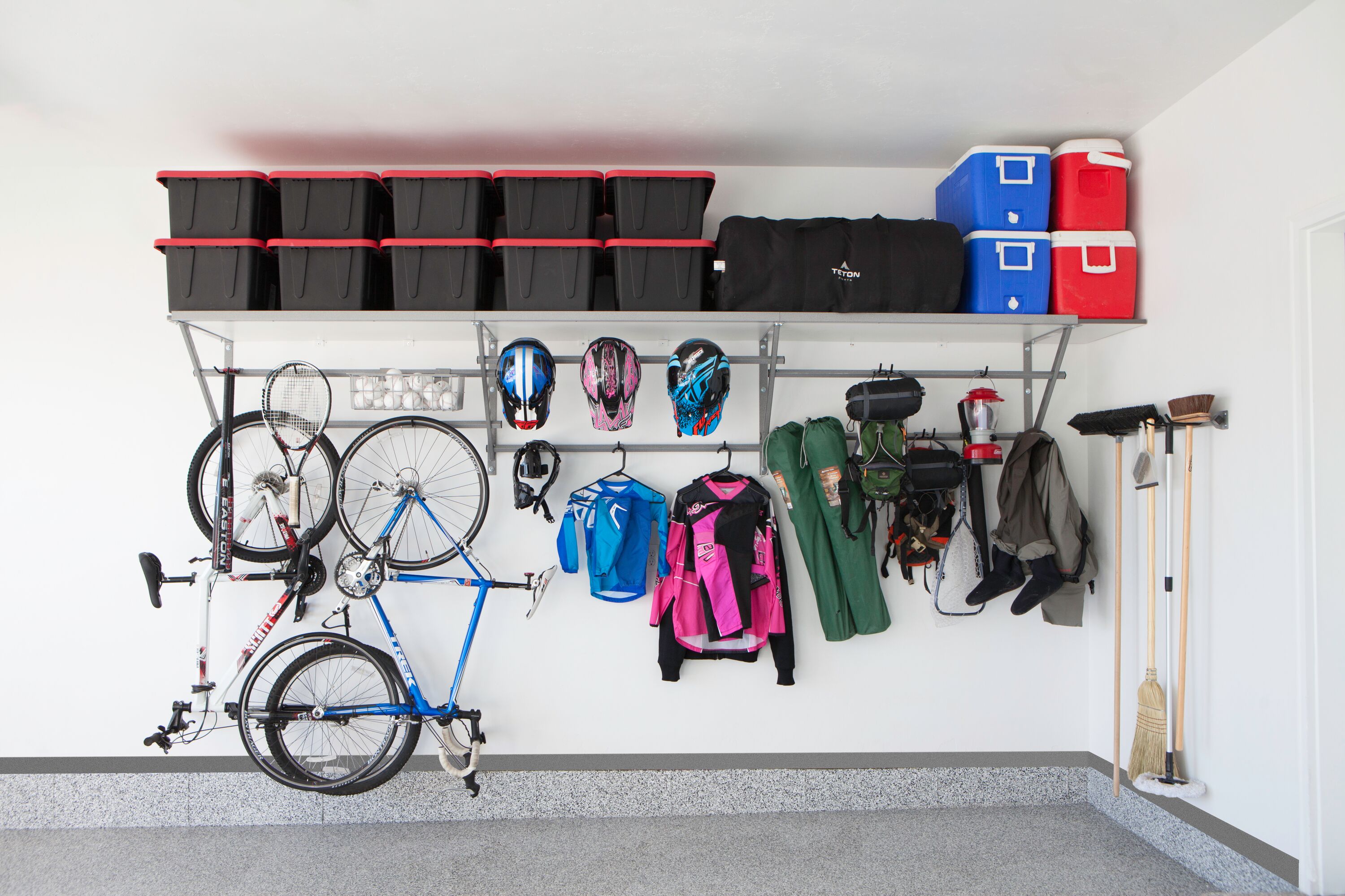 Garage overhead shelving with bikes and sports equipment hanging from it. 