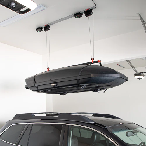 motorized lifter lifting rooftop storage off of a car. 
