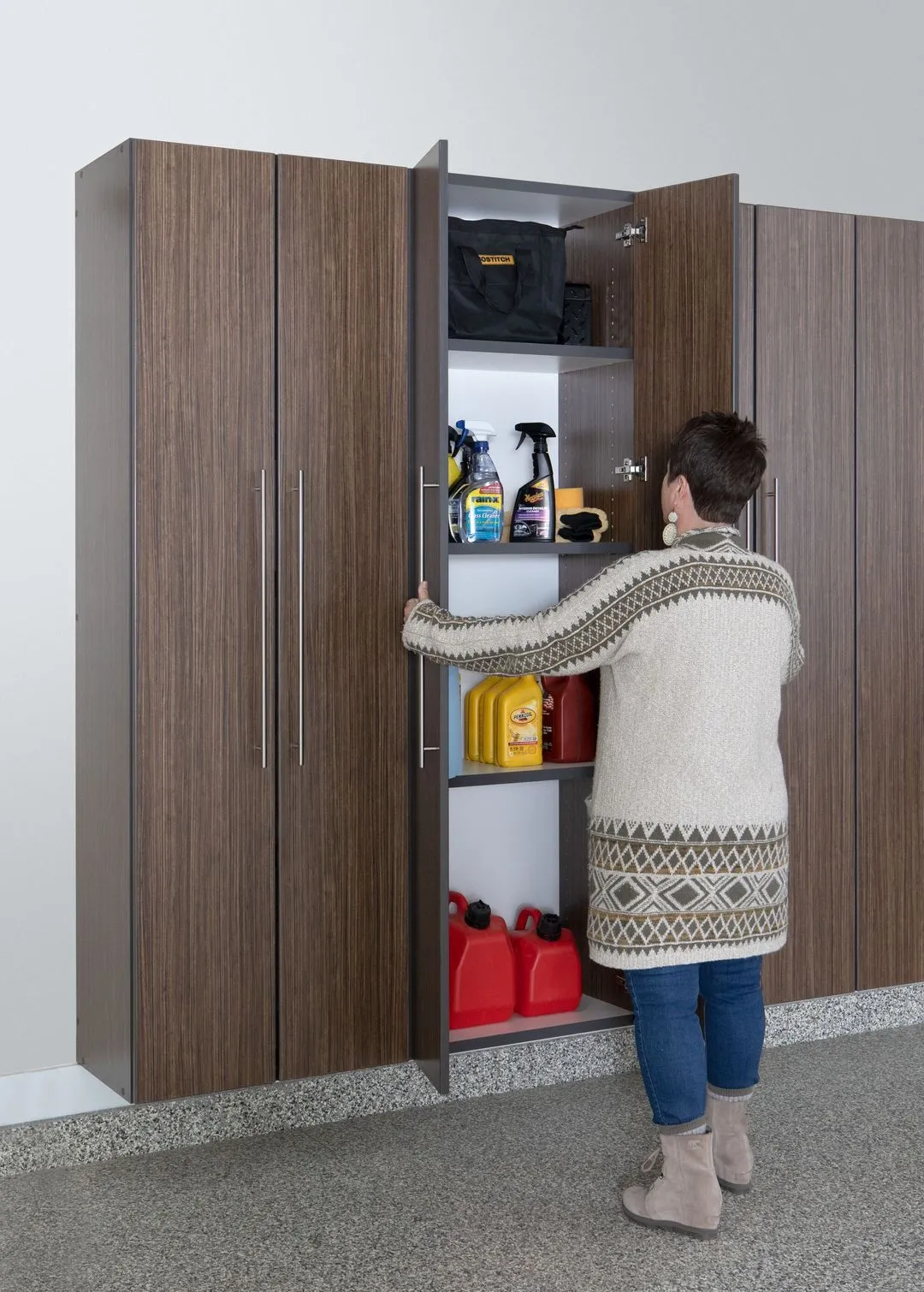 Woman putting cleaning supplies in a cabinet. 