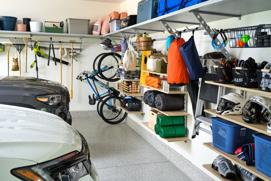 A neatly arranged garage with wall-mounted shelves, hanging storage for tools and sports equipment, and a securely mounted bike rack. Efficient garage layout and professional organization create a functional and accessible space.