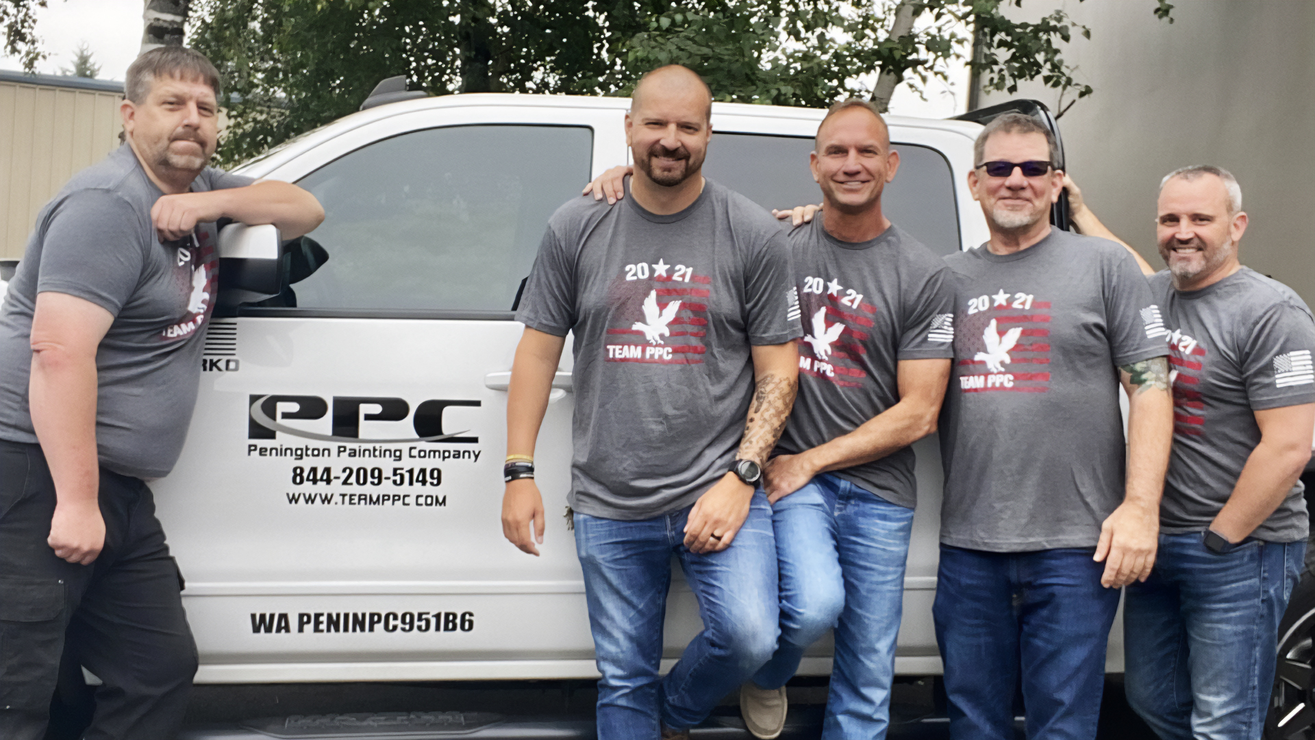 Five men in matching gray "Team PPC" shirts stand cheerfully by a company truck. The mood is friendly and casual, suggesting teamwork.