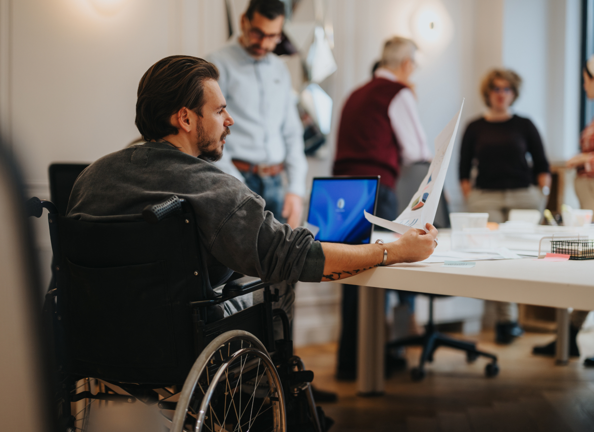 A man in a wheelchair looking at a document in an office setting