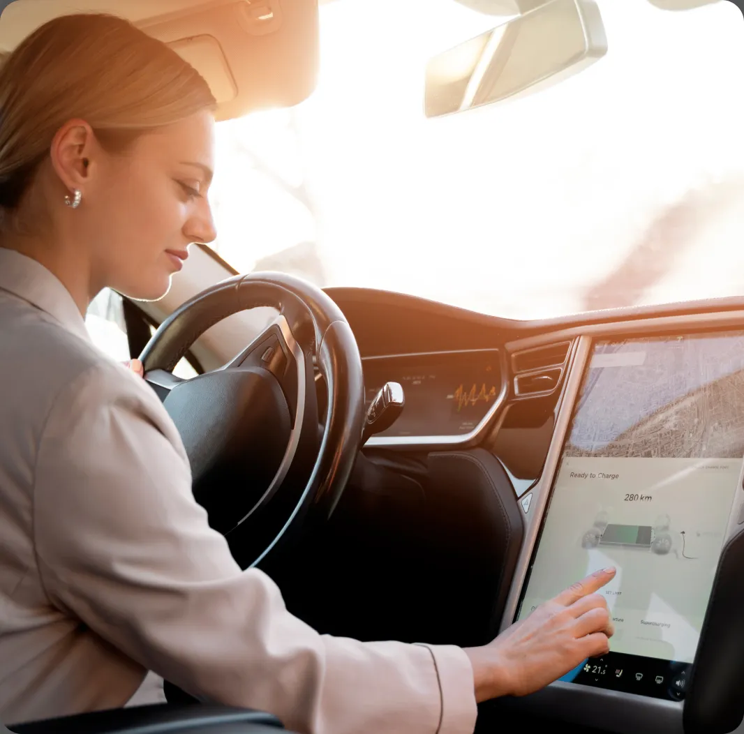 A woman in a car uses a touchscreen on the dashboard.