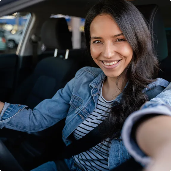 A woman in a car wearing a blue jacket and striped shirt.