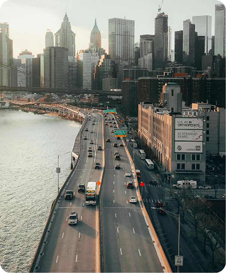 A bridge over a river with a city skyline in the background.