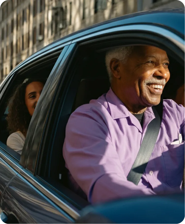 A man in a purple shirt is driving a car.