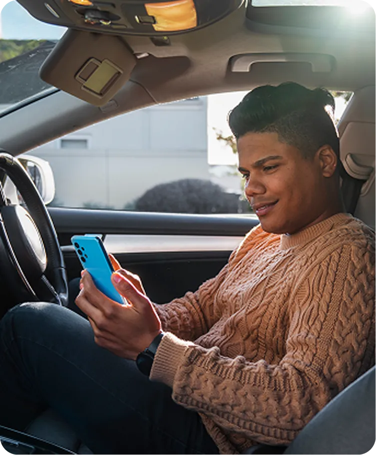 a man sitting in a car looking at his phone