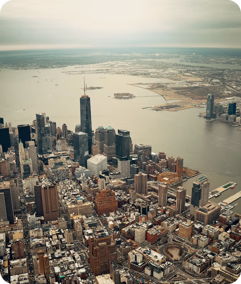 Aerial view of New York City with skyscrapers, the One World Trade Center, and the Hudson River.
