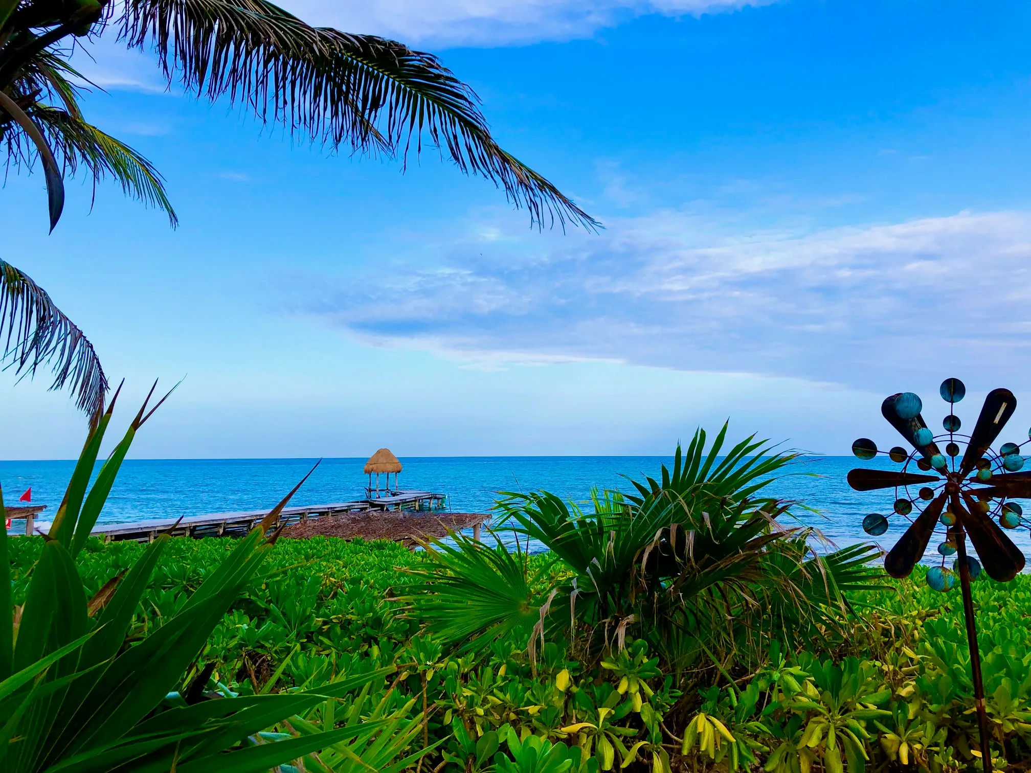 A view of a beach with a windmill in the foreground.