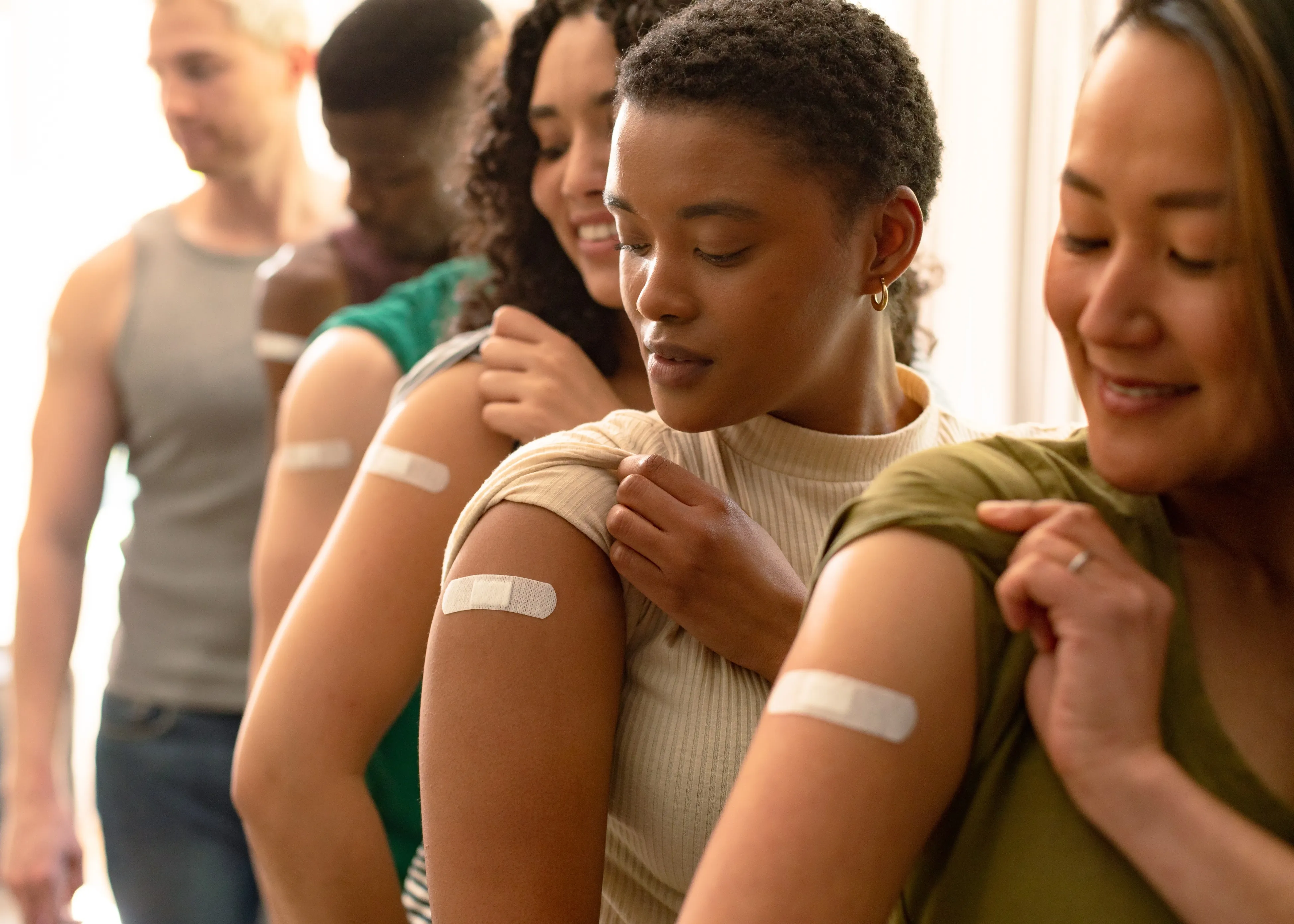 A group of women standing next to each other with band aids on their arms