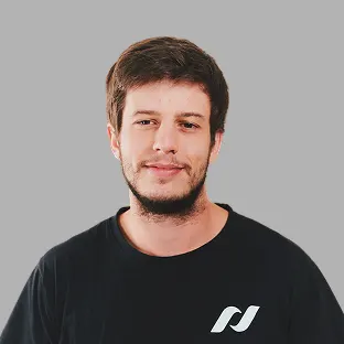 Retrato de un integrante de Neocoast con buzo negro con logo institucional, posando frente a fondo gris.