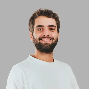 Retrato de un miembro de Neocoast con camiseta clara y barba, posando frente a fondo neutro.