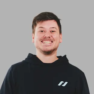 Colaborador de Neocoast con buzo negro institucional y una gran sonrisa frente a fondo gris.