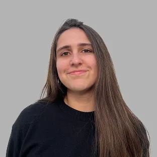 Trabajadora de Neocoast con sweater negro y cabello suelto, sonriendo frente a fondo gris claro.