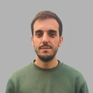 Miembro del equipo de Neocoast con buzo verde y expresión seria, posando frente a un fondo gris neutro.