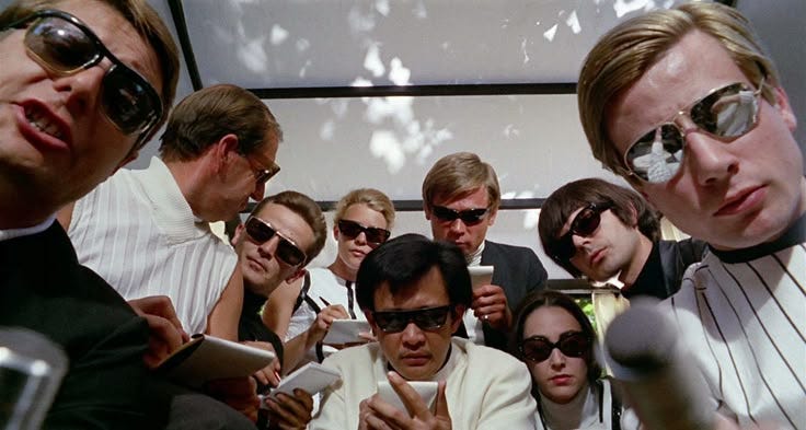 This may contain: a group of people sitting next to each other in front of microphones and cell phones