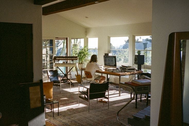 This may contain: a woman sitting at a desk in front of a computer monitor on top of a wooden table