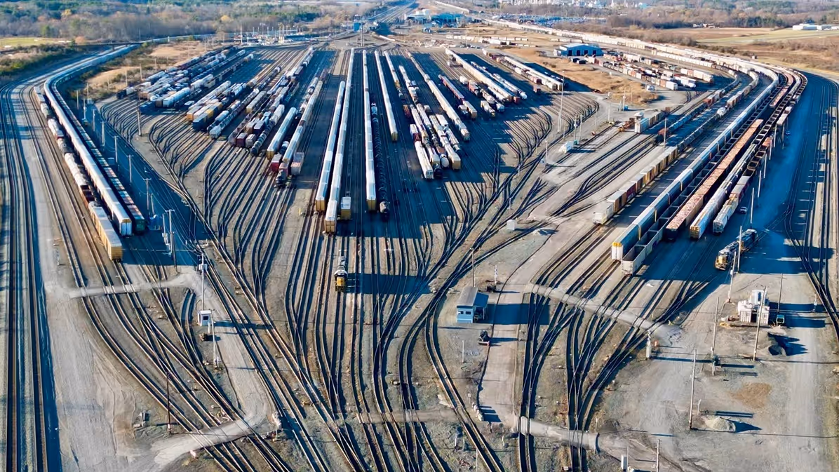 Aerial view of a freight train yard featuring numerous cargo trains and intersecting railway tracks in a vast, open landscape.