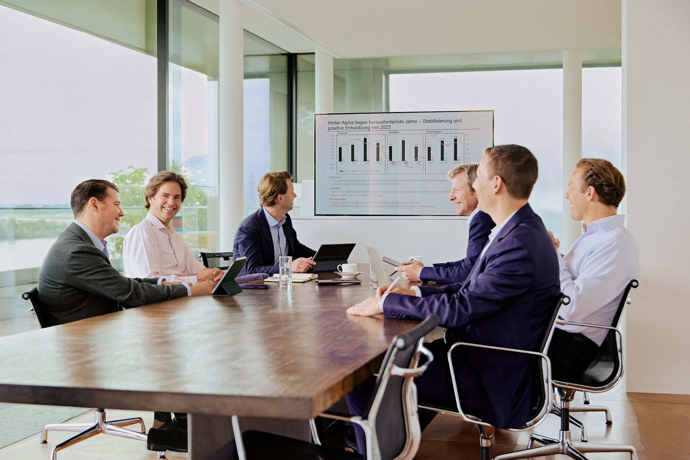 Das Team von Companion Unternehmenskapital sitzt an einem Konferenztisch und verfolgt eine digitale Präsentation zur Unternehmensstrategie auf einem großen Bildschirm.