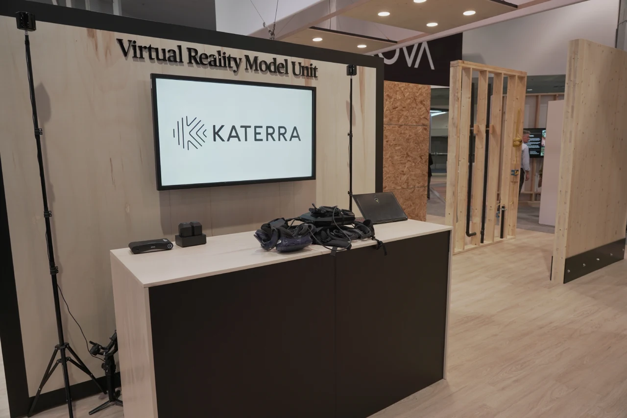 Virtual Reality Model Unit display with Katerra logo on screen and VR equipment on desk in an exhibition space.
