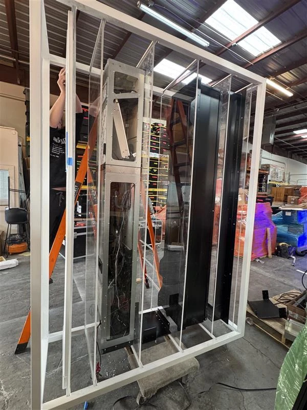 Person assembling or inspecting vertical black and white panels inside a large white frame in an industrial workshop.