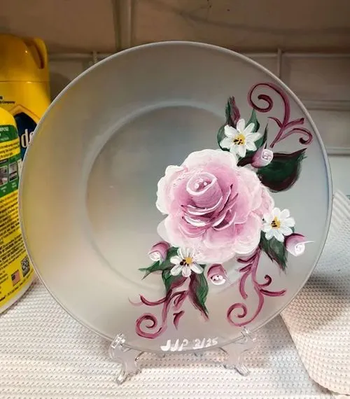 Frosted glass plate on a display stand, hand-painted with a large pink rose, white blossoms, and swirling burgundy vines.