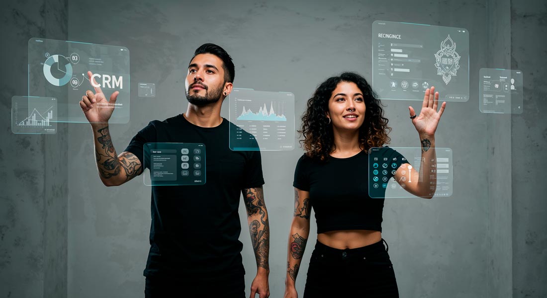 Homem e mulher interagindo com painéis holográficos digitais exibindo gráficos, CRM e dados, em um fundo cinza com parede de concreto.