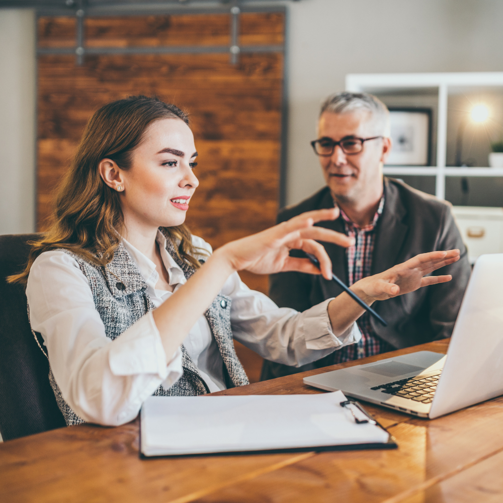 Two people talking at a desk