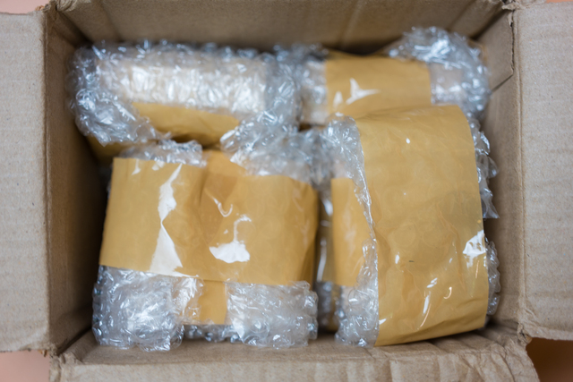 Packing fragile items with plastic air bubble wrapped and adhesive tape in box