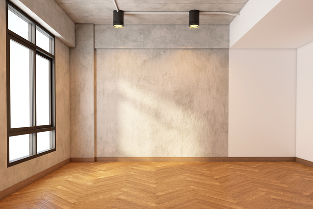 Empty room with bare cement wall and pattern wood floor.