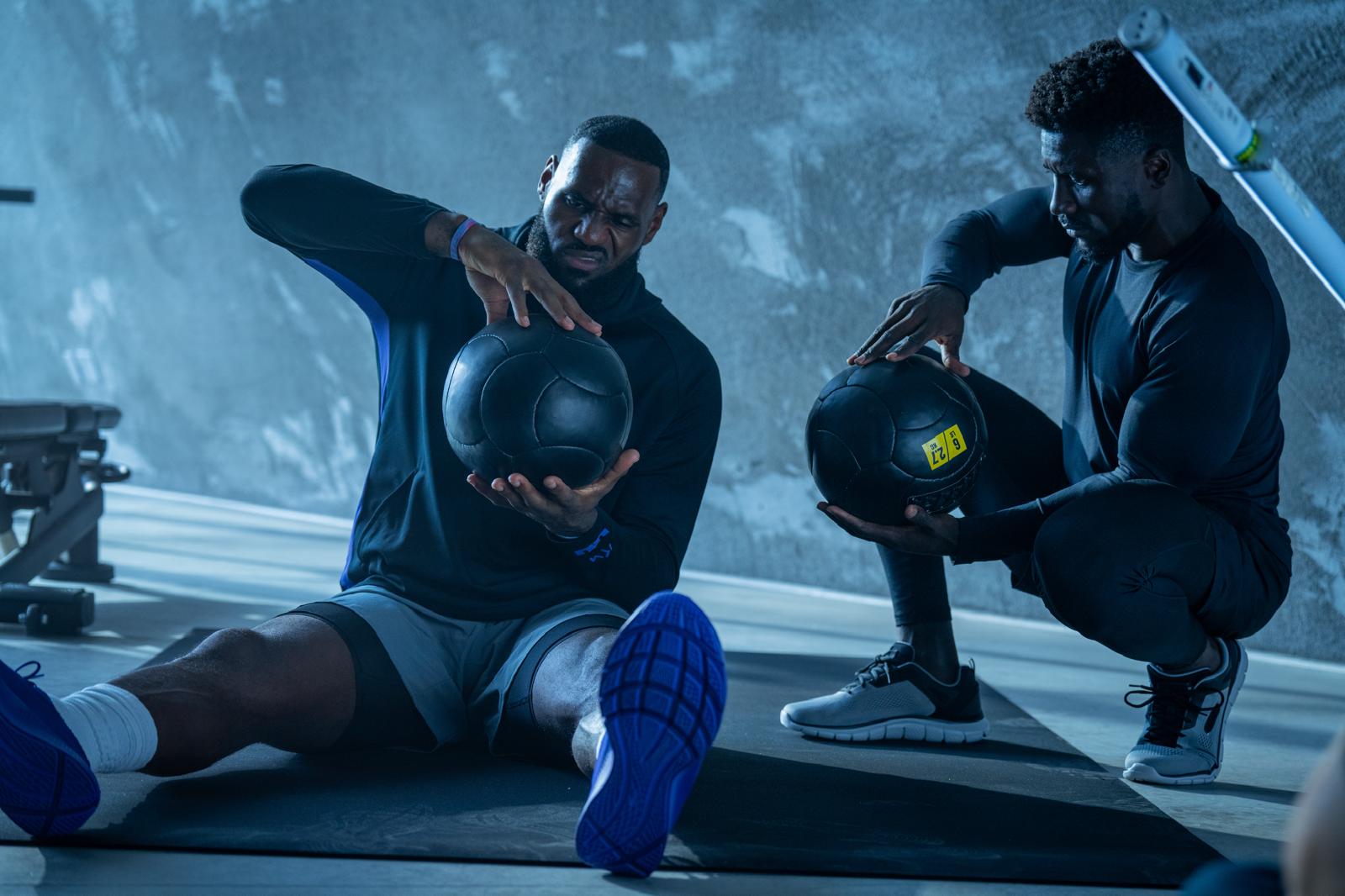 Sadiq A and Lebron J sited and squatting teaching each other how to hold a basket ball.