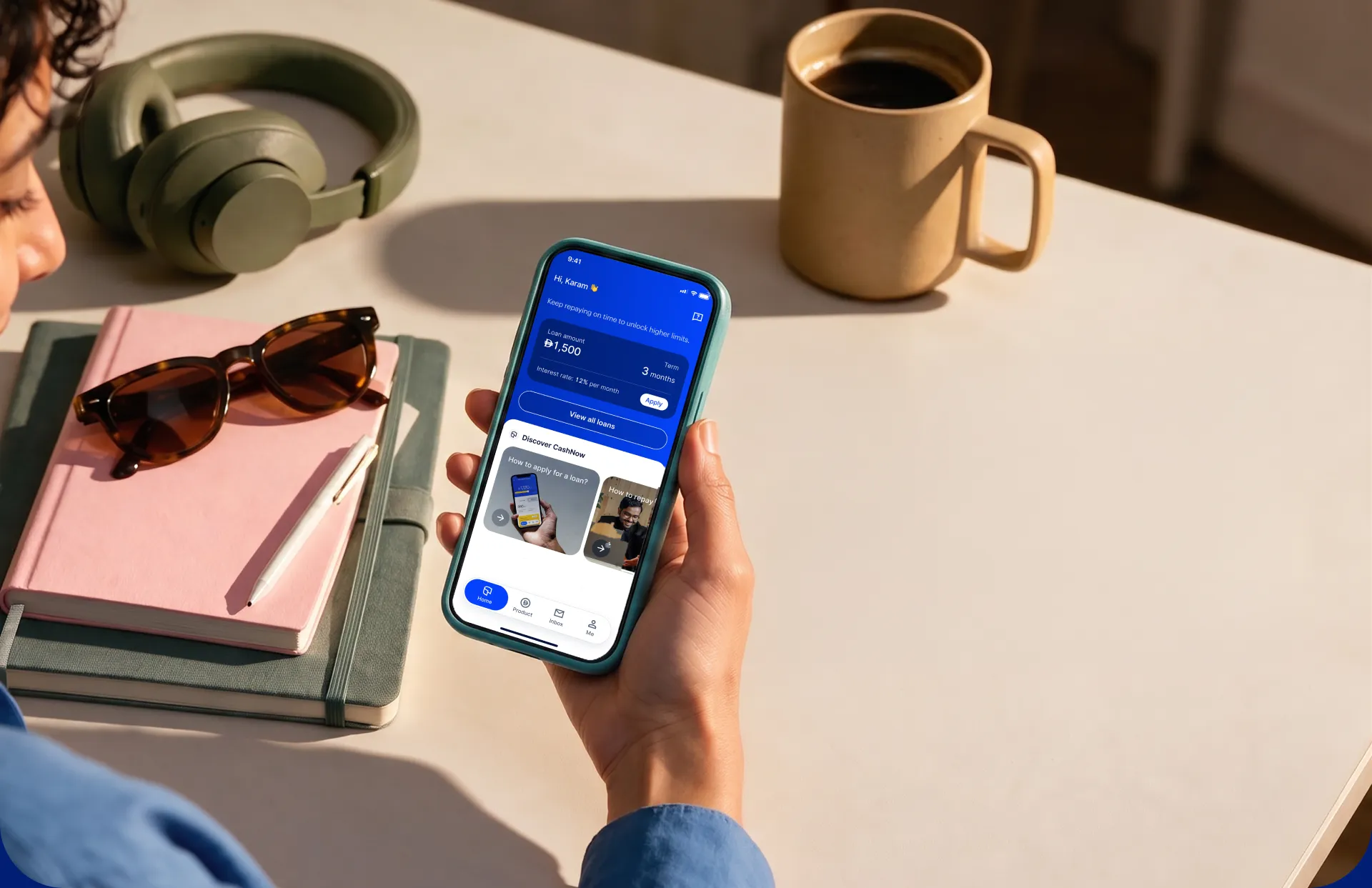 Person holding a phone with the CashNow app open at a desk