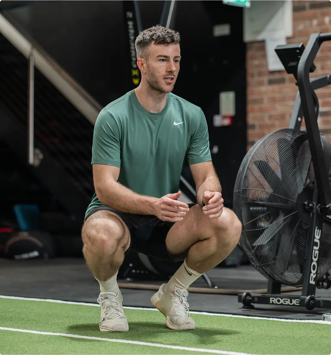 Personal trainer squatting on the gym floor