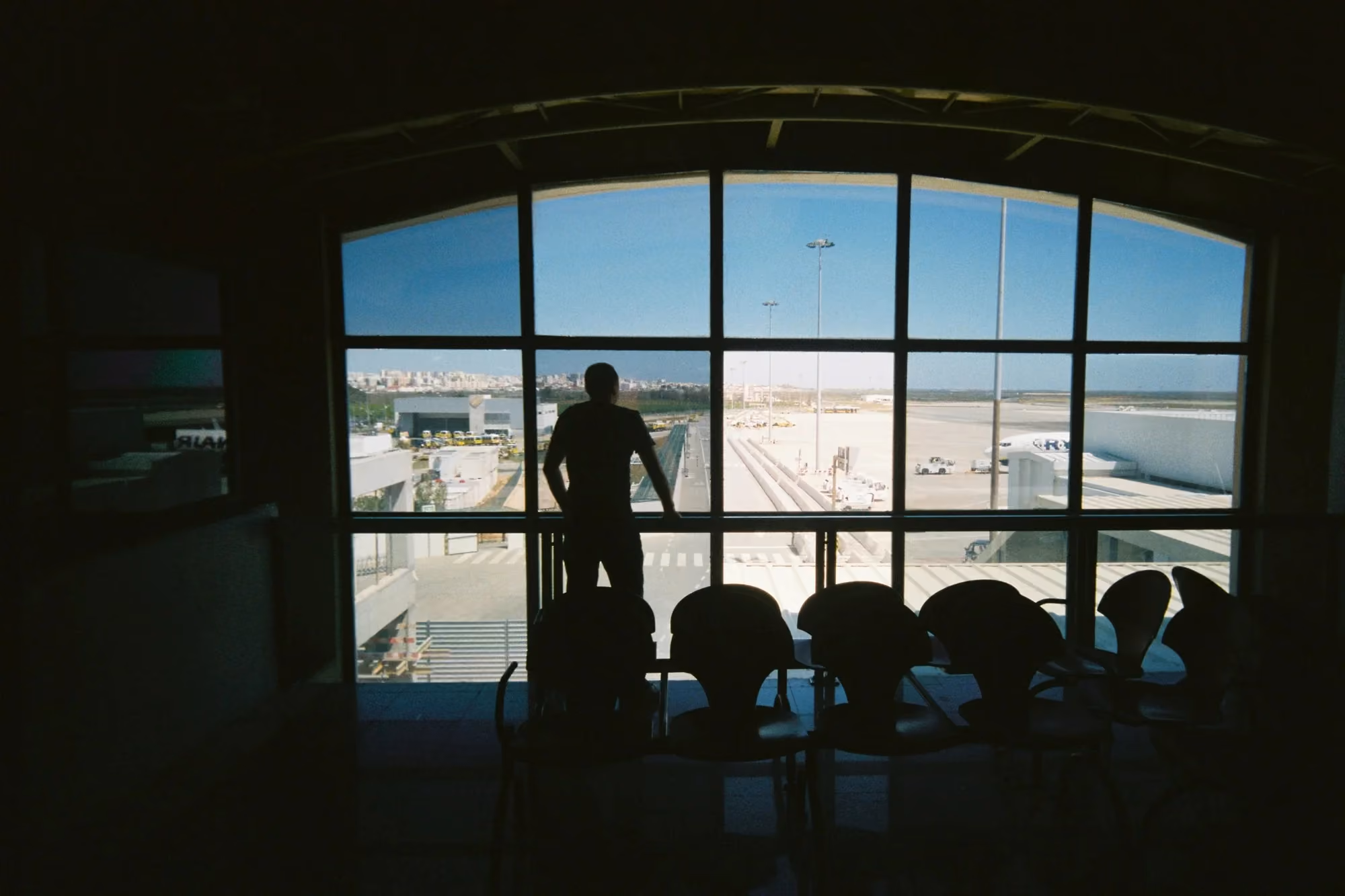 Traveller looking across an airport apron through terminal windows