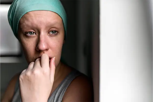 A woman with a late cancer diagnosis looks frightened and sad considering the future
