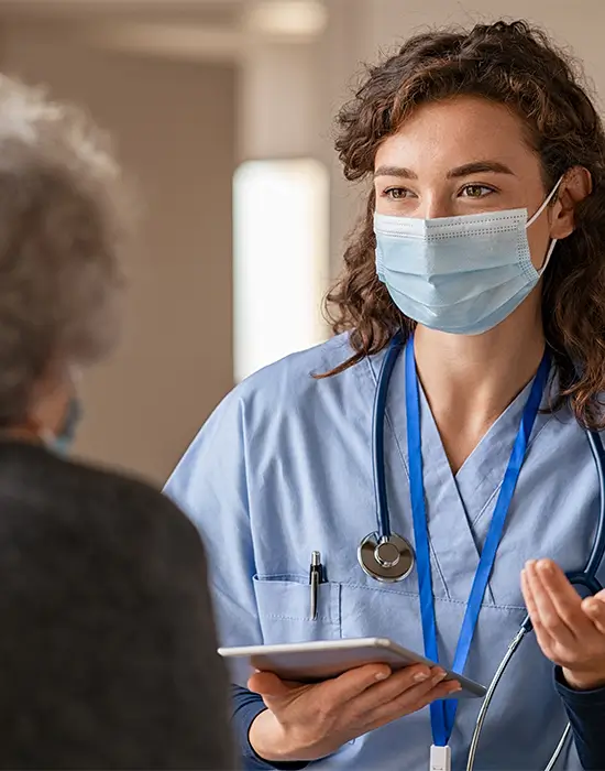A female doctor uses information given by an AI system to care for an elderly female patient