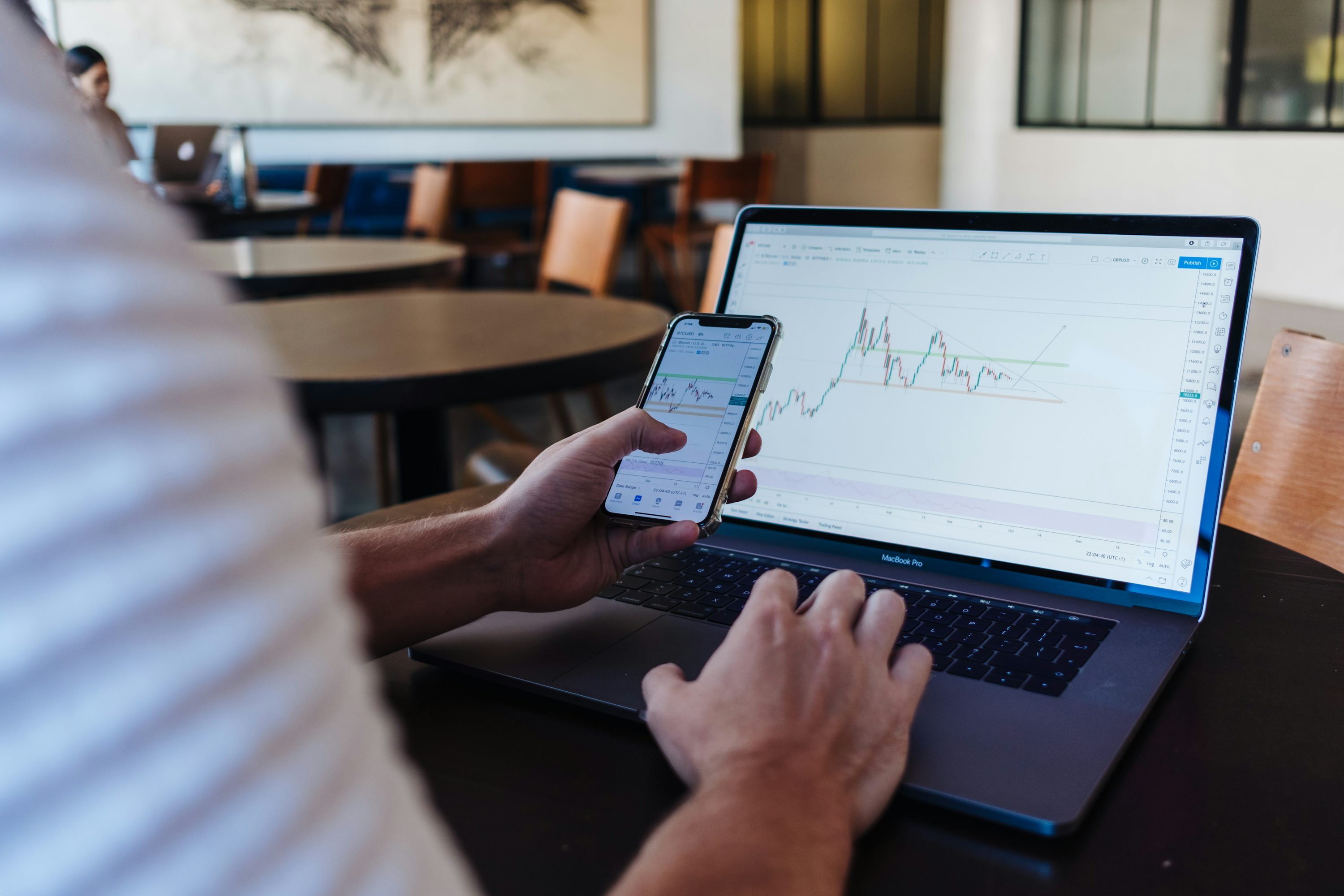 person using smartphone and MacBook Pro - How to Choose the Best Trading Strategy for Beginners