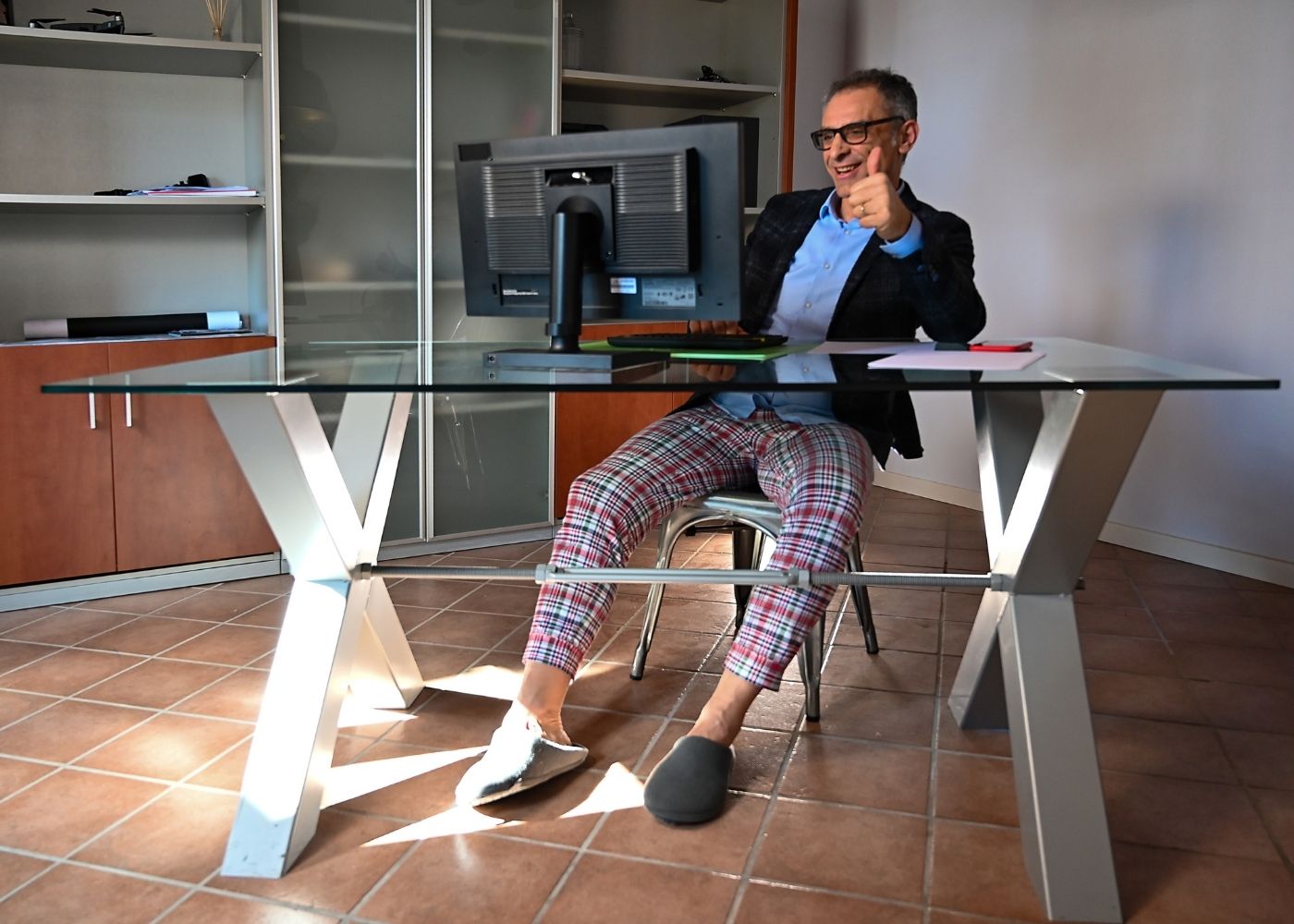 Un homme en télétravail portant un haut de costume et un pantalon de pyjama illustrant l'importance de la fléxibilité en entreprise