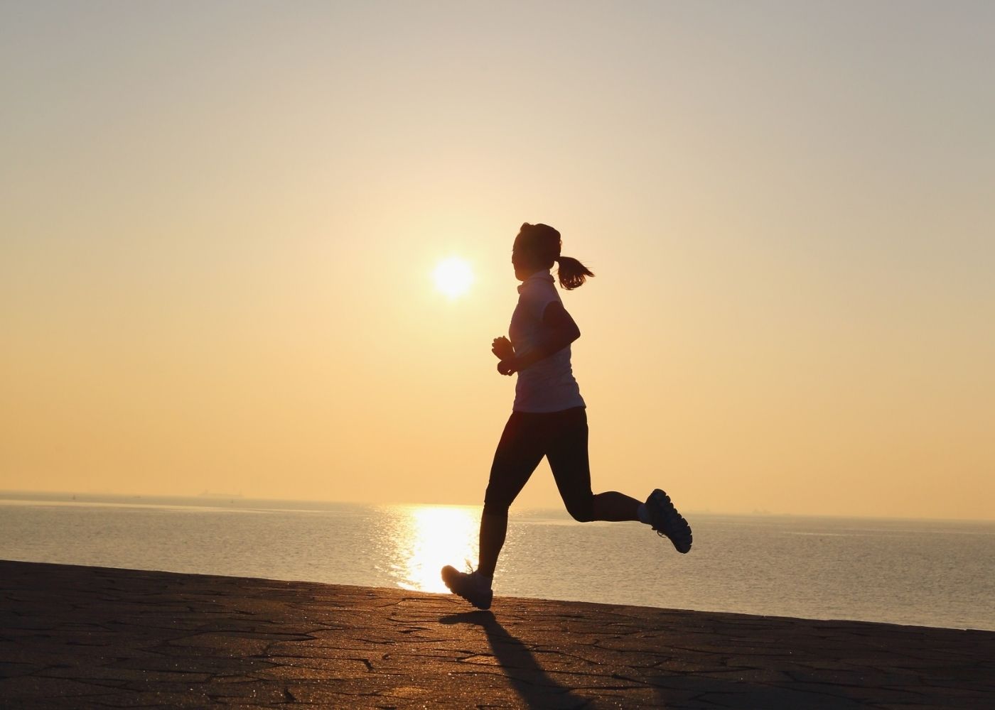 Femme faisant un footing sous le soleil matinal illustrant les bienfaits de la lumière naturelle pour le sommeil