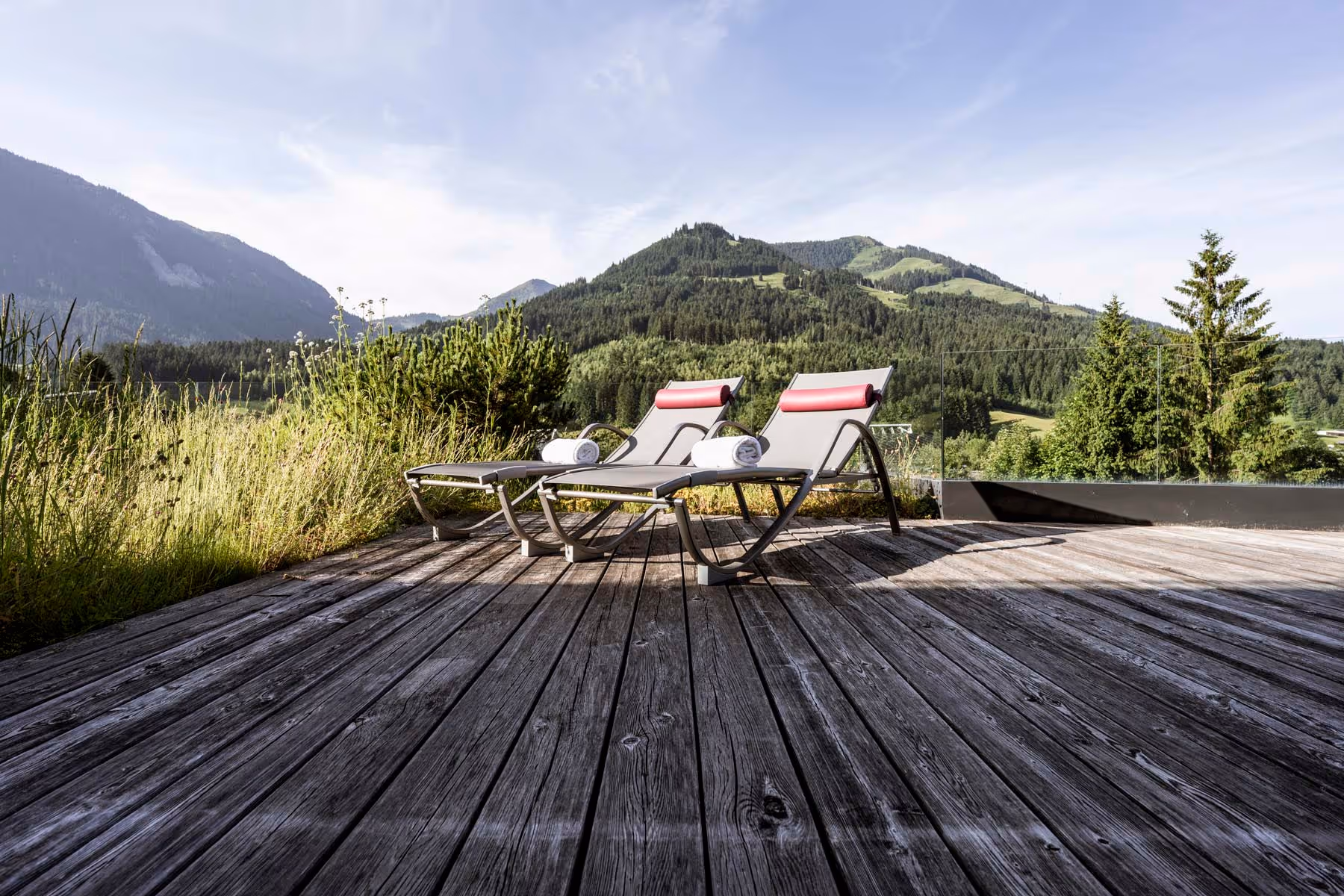 Zwei einladende Sonnenliegen auf der großen Terrasse des Hubertus Apartments Hahnenkamm.