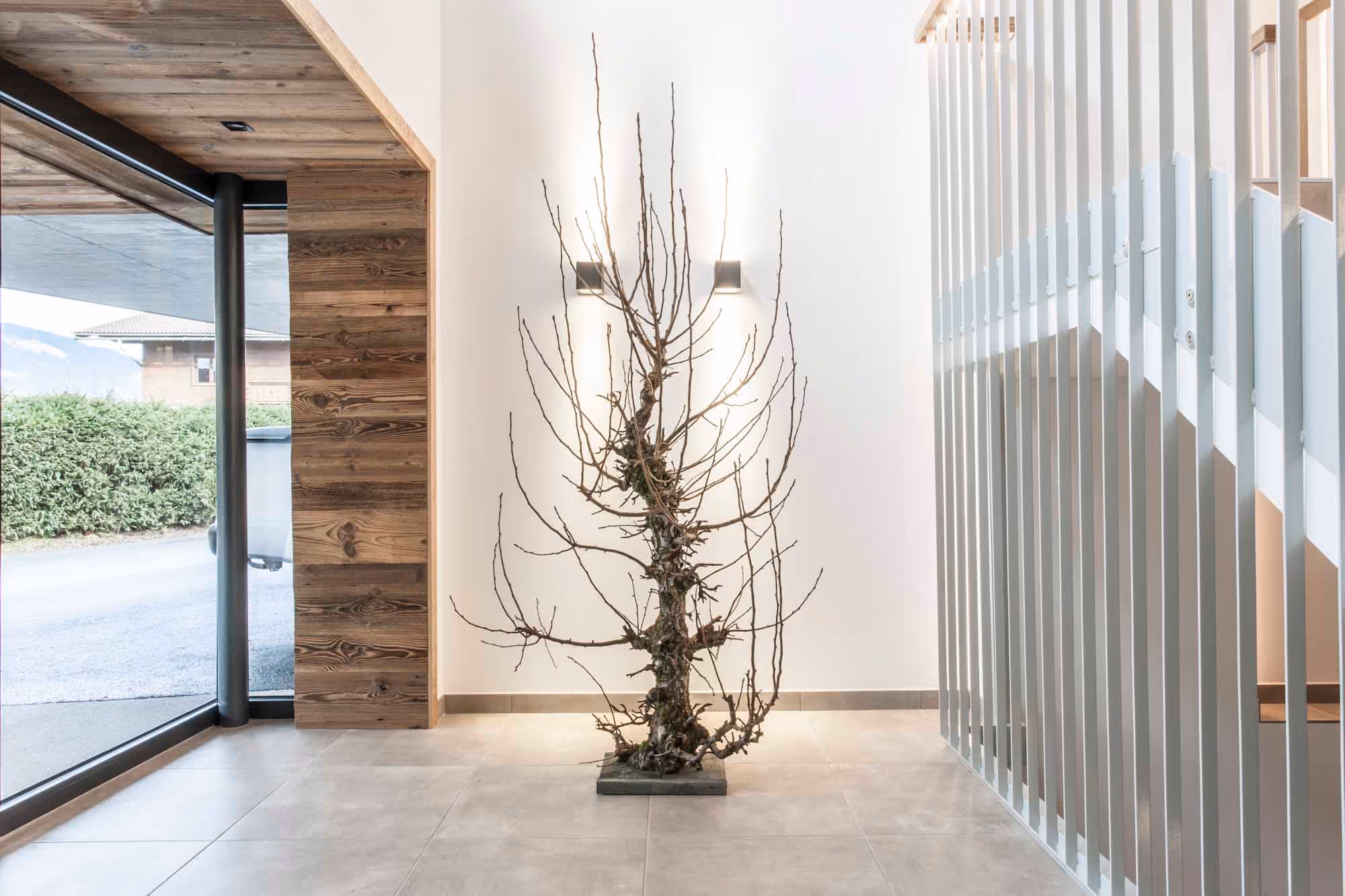 Ein blattloser Baum steht im Eingangsbereich der Hubertus Apartments.