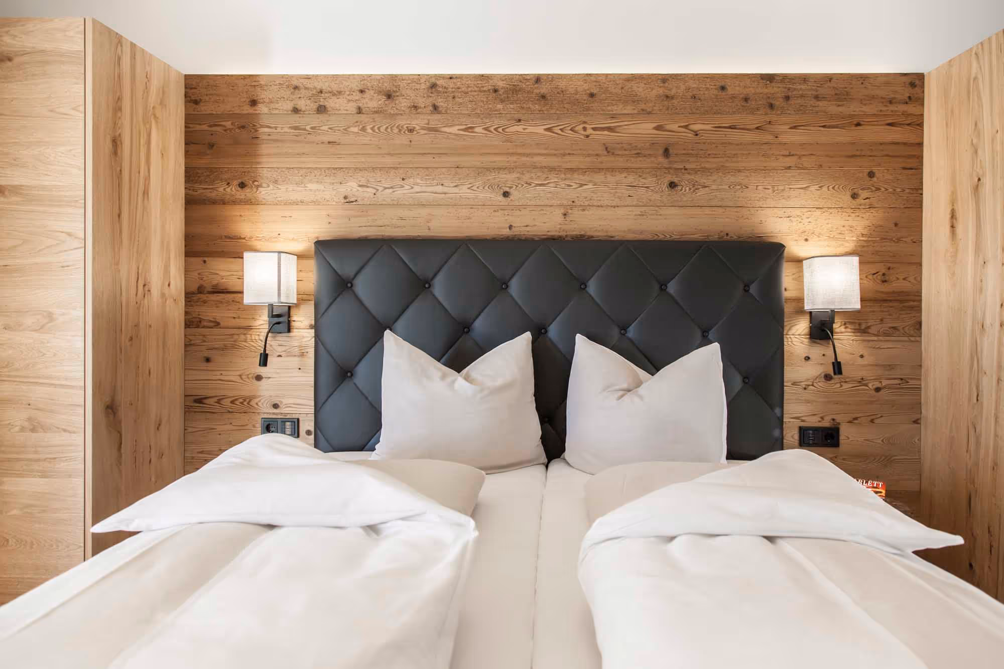 Warmes Schlafzimmer mit hochwertigem Boxspringbett im Hubertus Apartment.