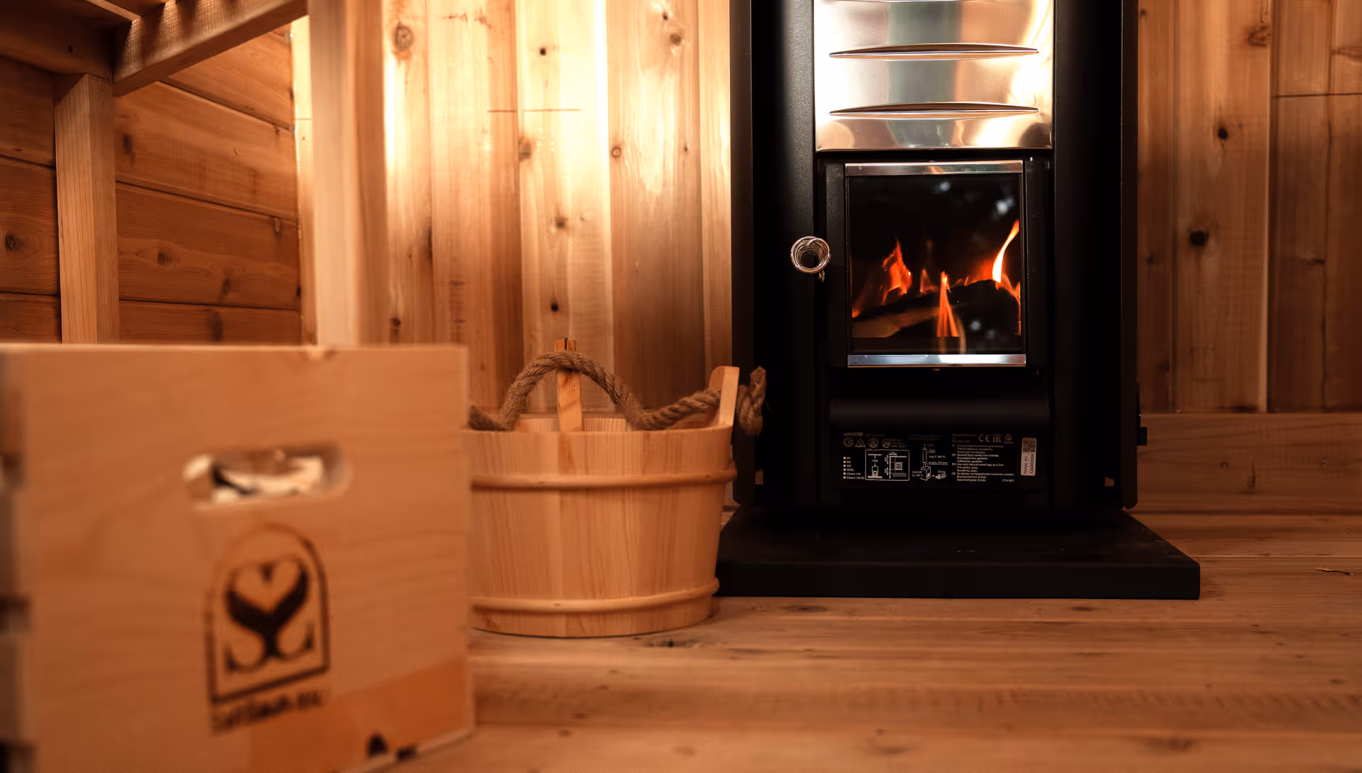 The interior of a sauna featuring a small, black wood-burning stove with a protective grate.