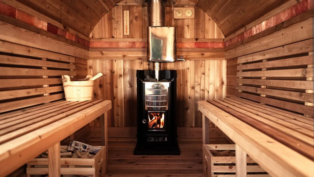 The interior corner of a wooden sauna, showing the benches and warm lighting on the wood panels.