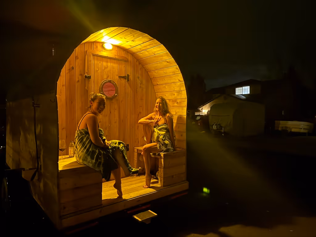 The empty interior of a barrel sauna glows with a warm, inviting light in a dark setting.