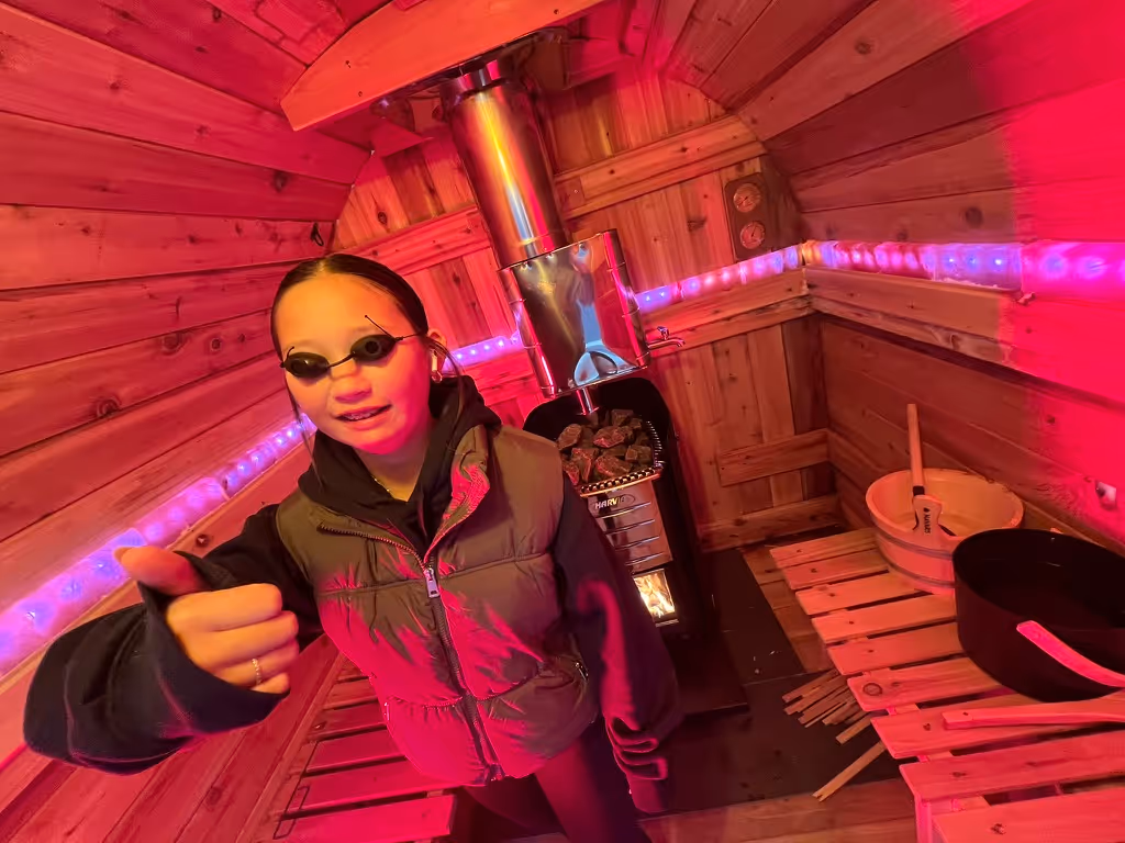 A woman in a sauna with a thumbs up.
