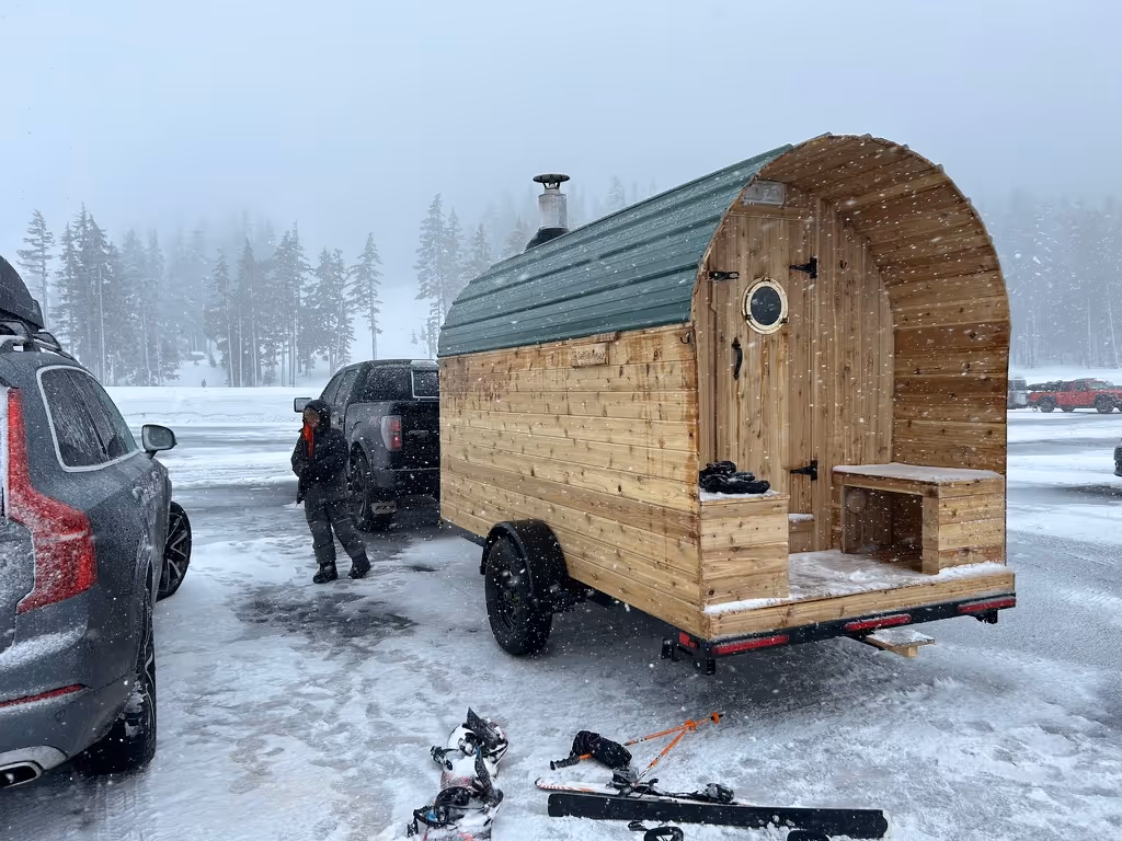 A small wooden outhouse sitting on top of a snow covered field.