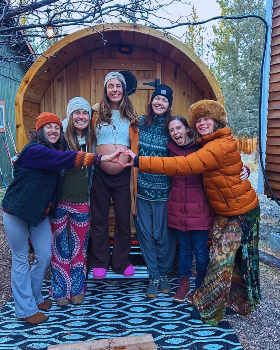 A group of women standing next to each other in front of a barrel.