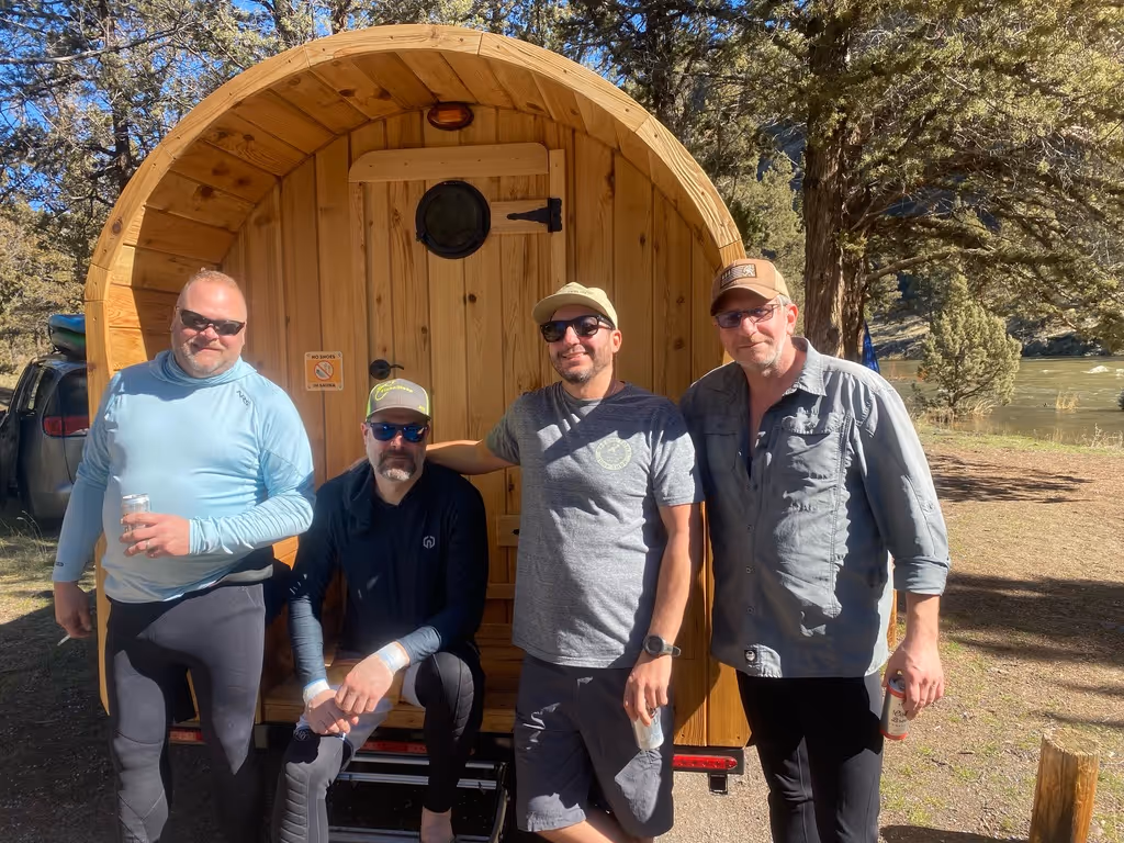 A group of men standing next to each other in front of a wooden barrel.