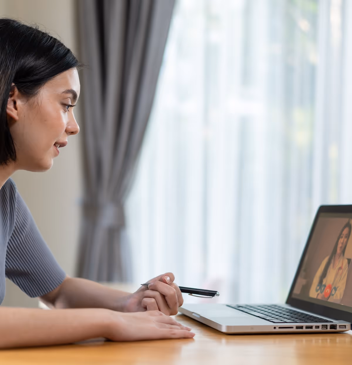 Frau guckt auf einen Laptop und ist in einem Online Meeting